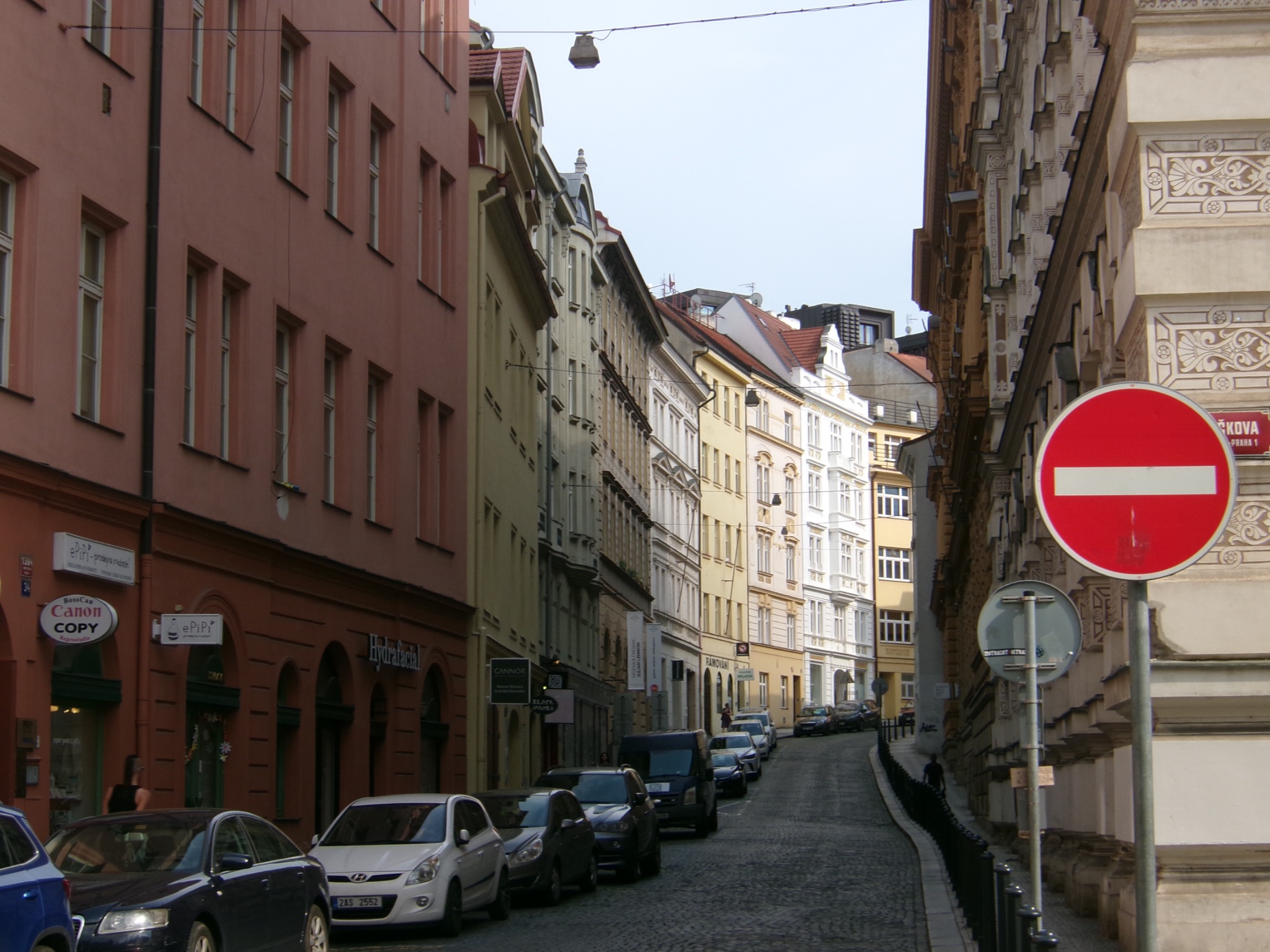 A narrow street lined with pastel buildings and parked cars