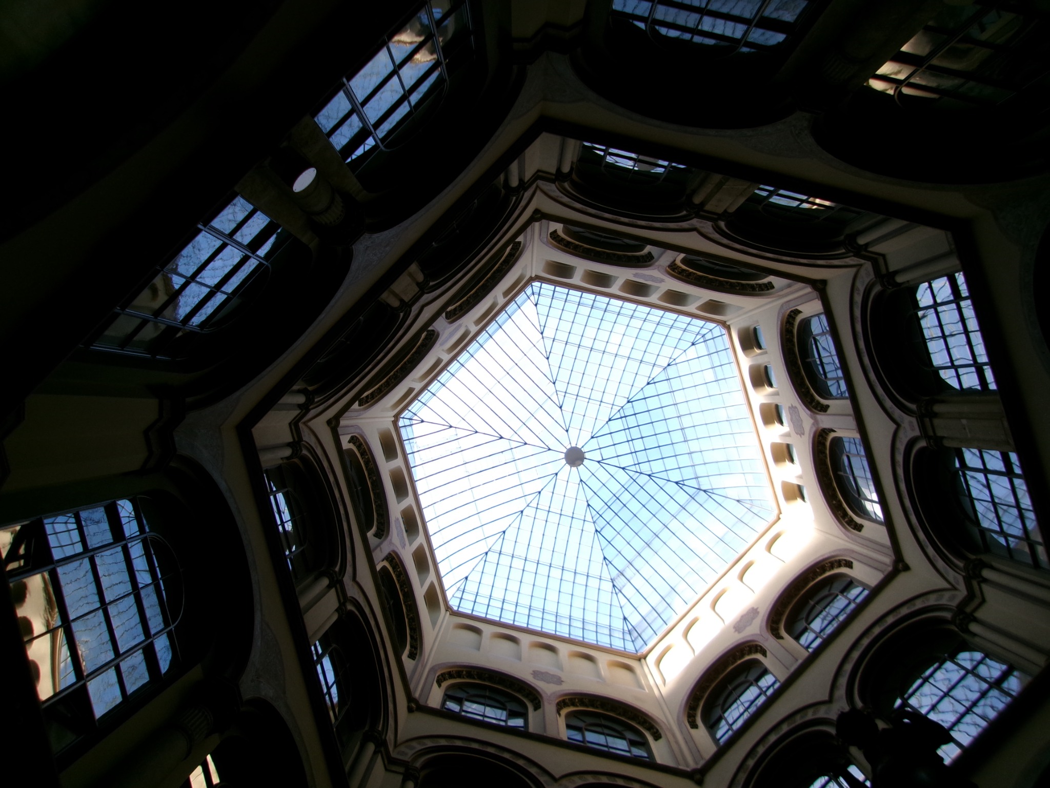 Looking upward through a dark interior toward an octagonal glass roof