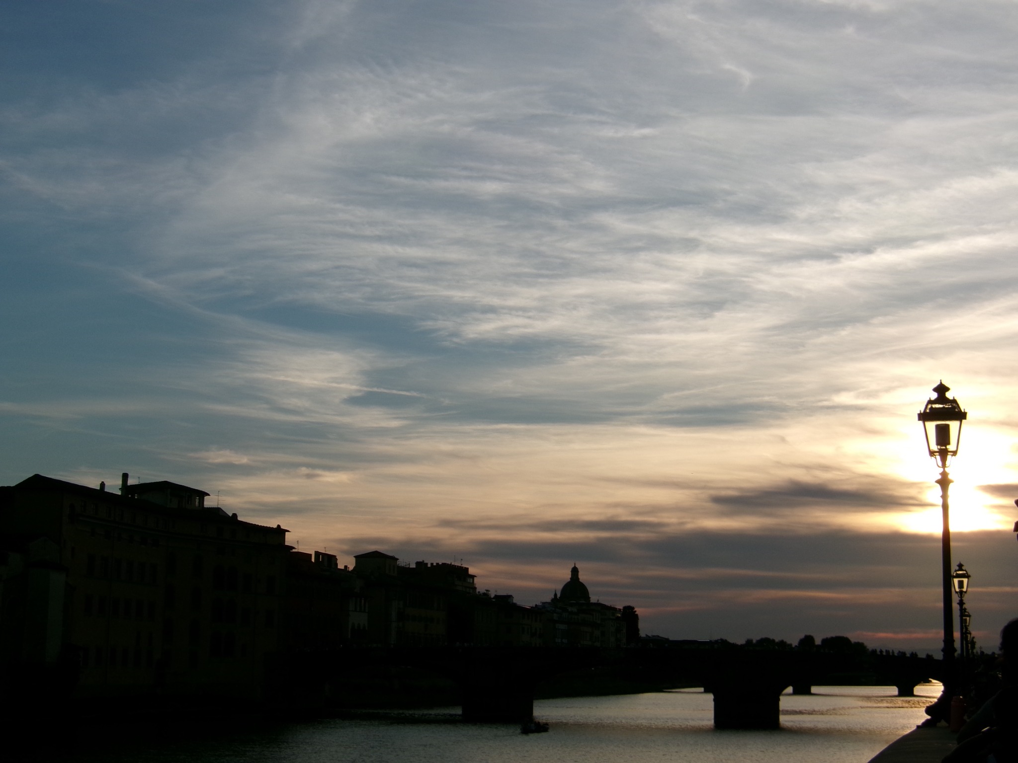 A bridge and river at sunset beside a glowing streetlamp
