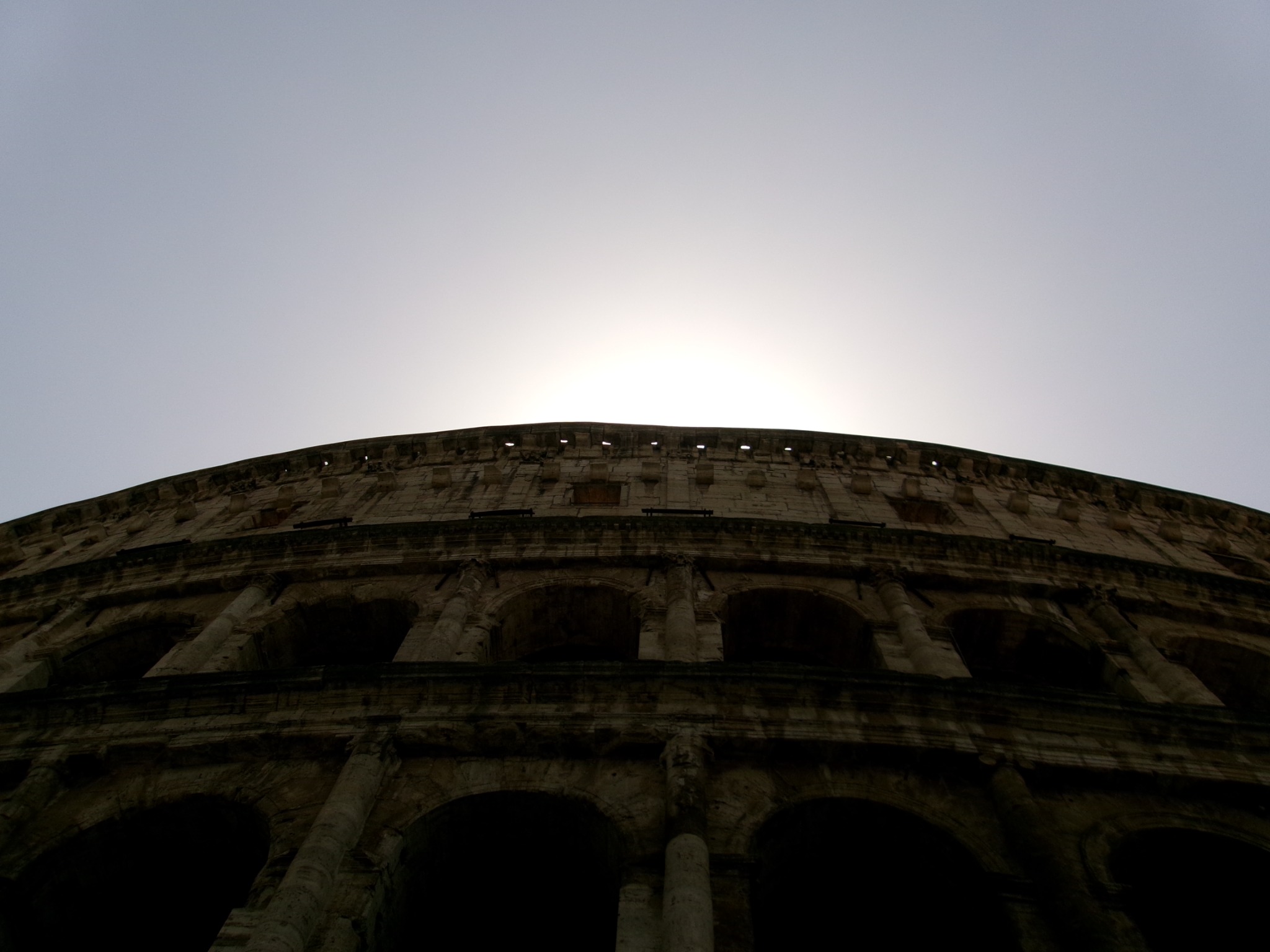 Sunlight above the curved exterior of an ancient stone amphitheater