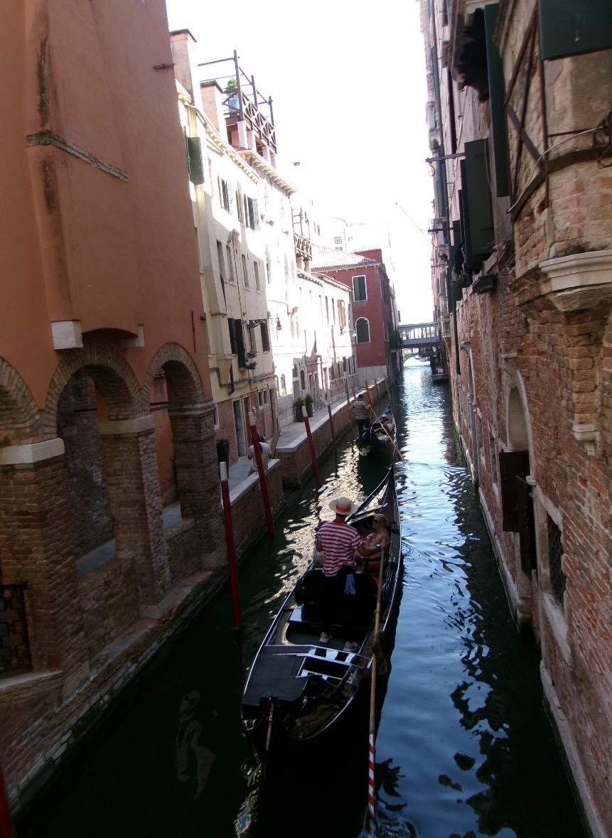 A gondola in a narrow canal between tall buildings