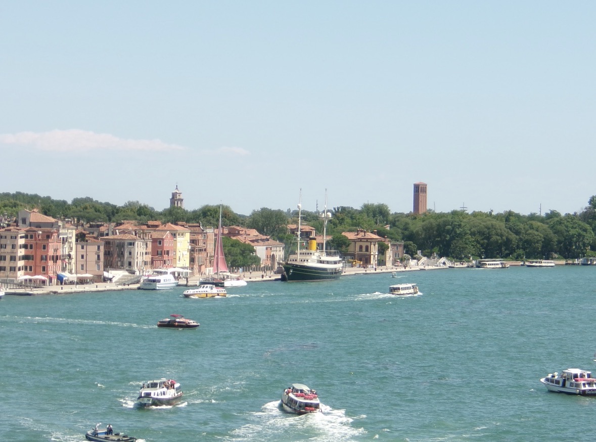Boats crossing blue-green water beside a waterfront town